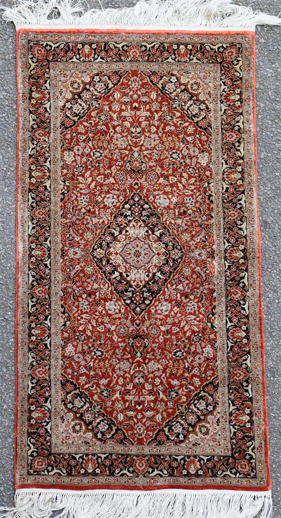 A Persian silk russet ground rug, 4ft 1in by 2ft 1in.